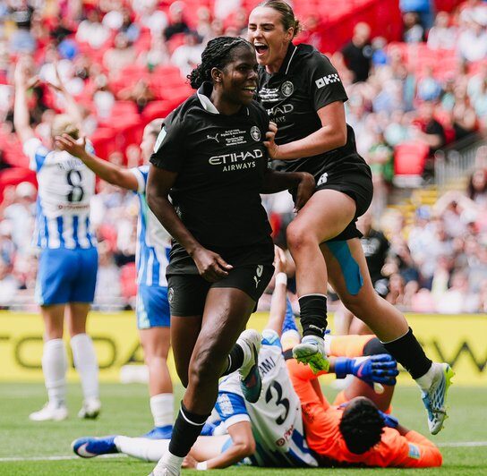 Manchester City players celebrate leaving Brighton goalkeeper Chaimaka Nnadozie on the floor 